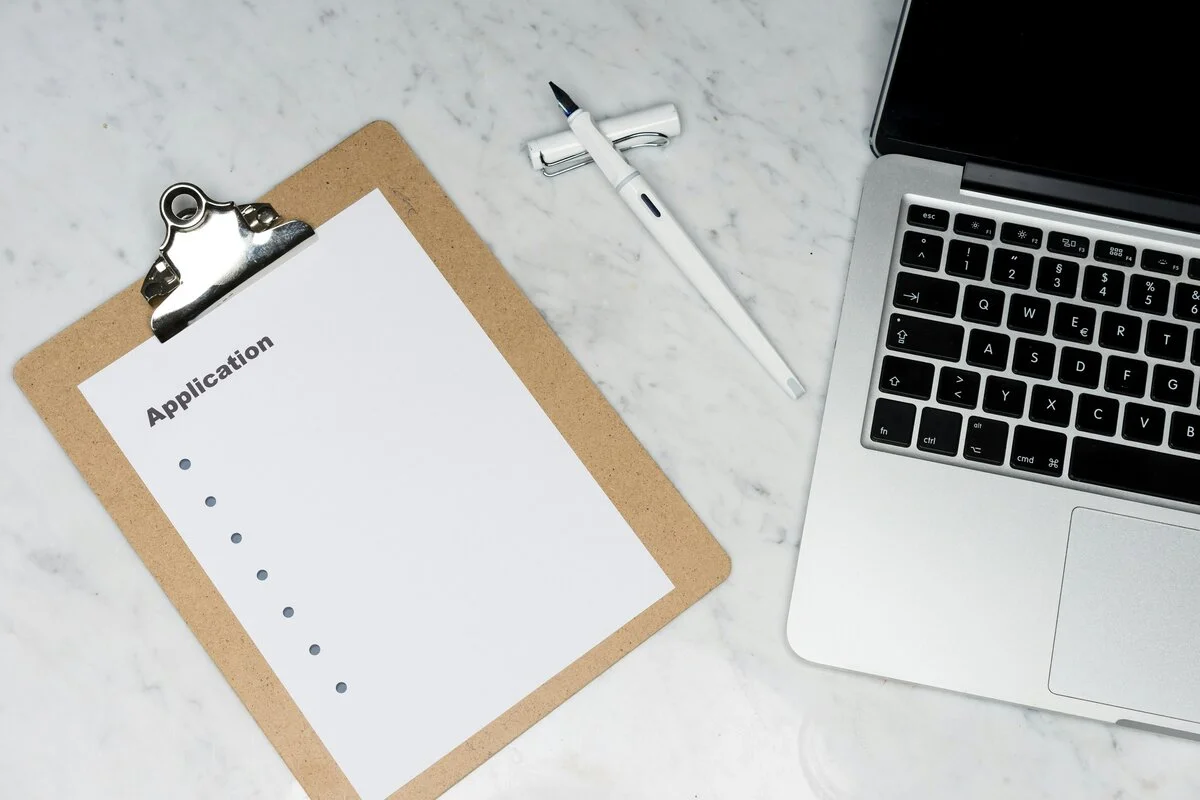 Professional writing a formal retirement letter with pen on paper, alongside career mementos symbolizing years of service