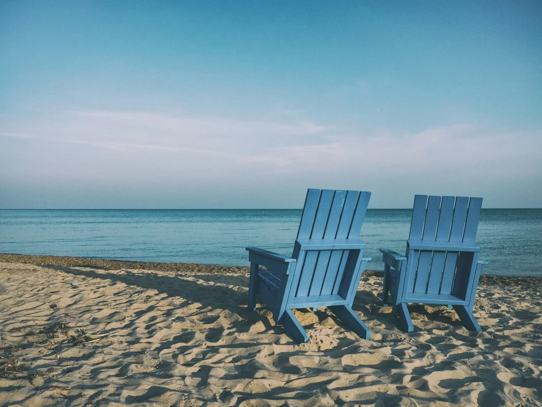 Happy senior couple laughing on beach at sunset, enjoying their retirement with a sense of humor and joy