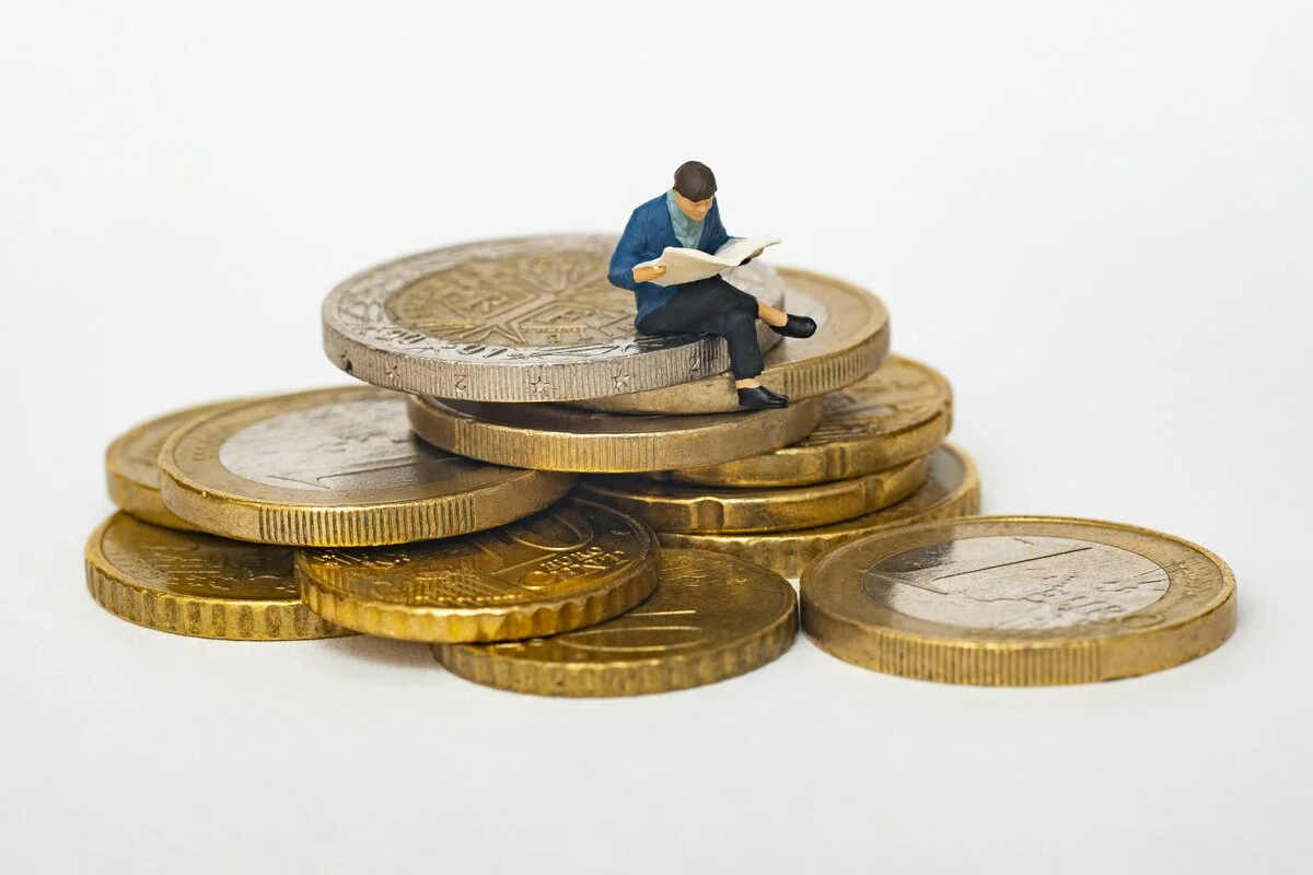 Money and coins with a magnifying glass focusing on rising price indicators, symbolizing the need for inflation protection strategies